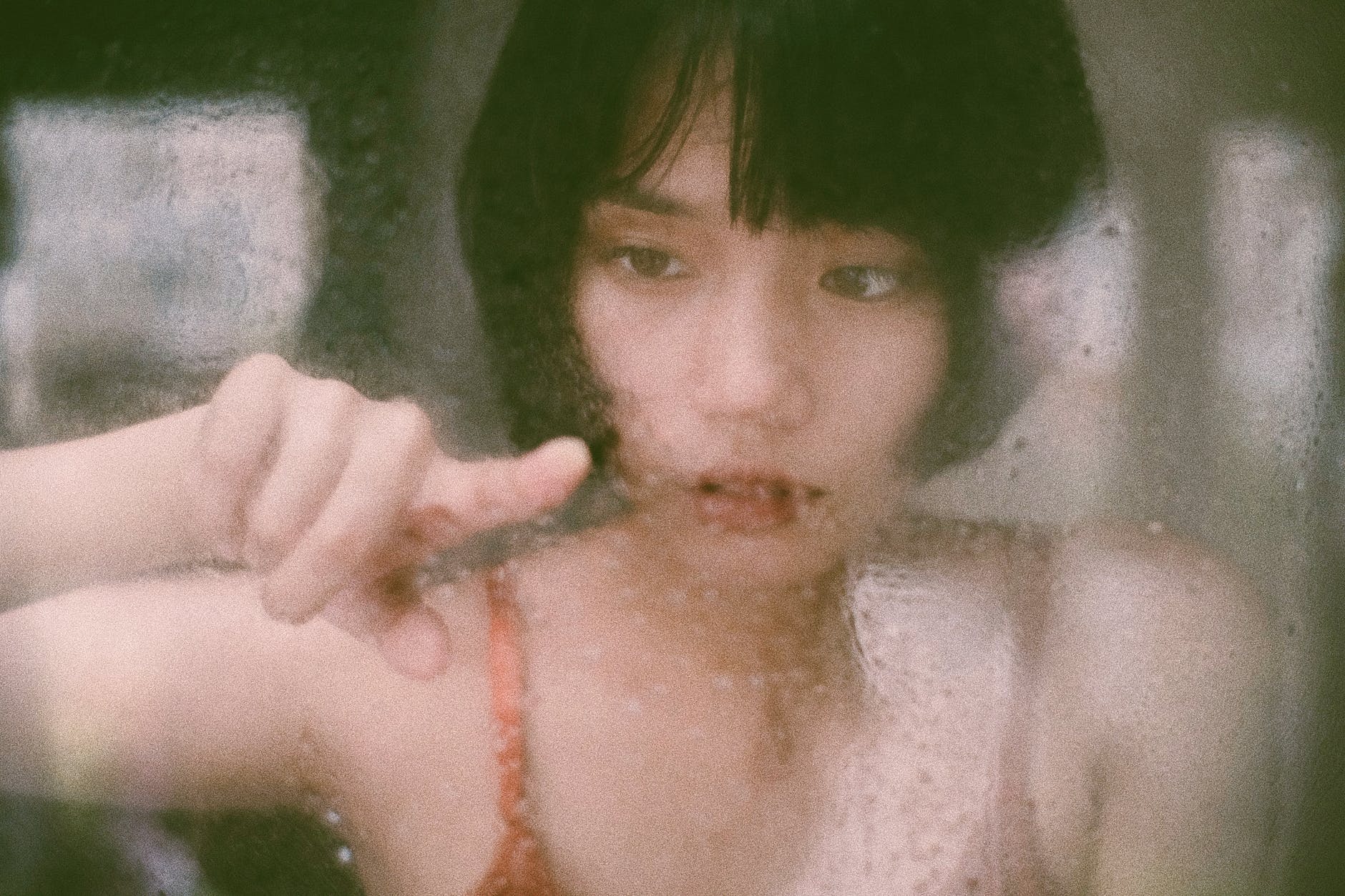 ethnic female touching wet window